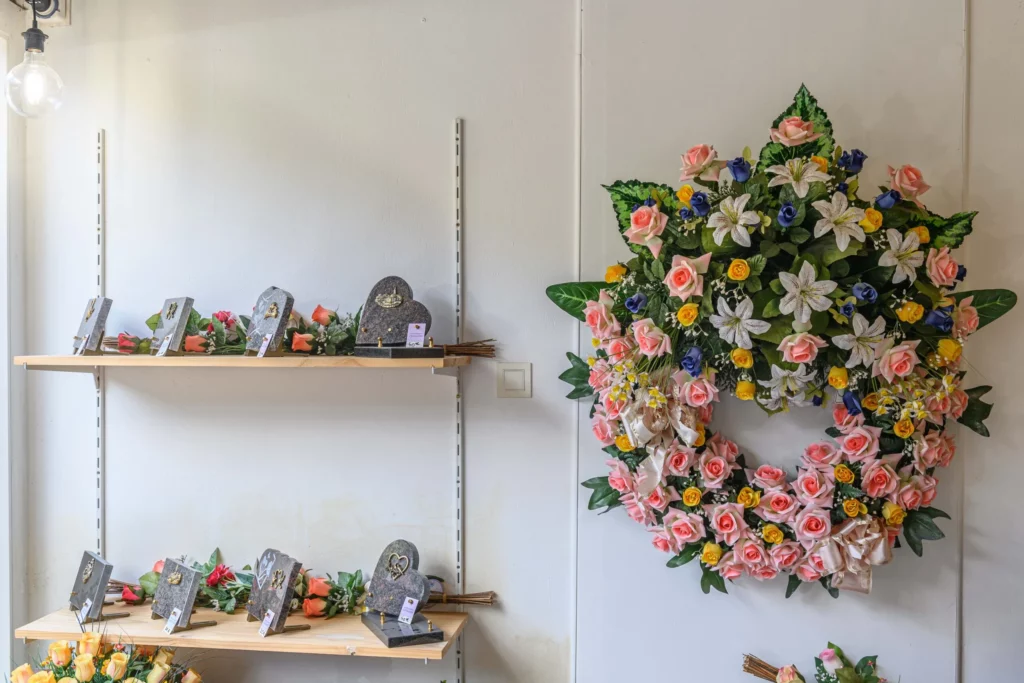 Plaques funéraires personnalisées et couronne de fleurs artificielles en exposition dans l'agence